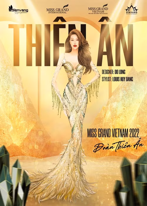 Đầm dạ hội của Thiên Ân cho chung kết vừa được hé lộ. Mẫu thiết kế được lấy cảm hứng từ chính tên của Thiên Ân - món quà quý giá được trời ban tặng. Với tone màu vàng đồng chủ đạo, mẫu thiết kế khai thác những đường nét uốn khúc mạnh mẽ biểu tượng cho ánh nắng mặt trời đang chiếu rọi, kết hợp cùng màu xanh ngọc lục bảo biểu trưng cho tình yêu hòa bình và sự sống. Mẫu thiết kế được dựng phom corset bên trong. Phần đuôi đầm được đính kết những chiếc lông vũ dài sơn nhuộm màu vàng đồng. Những họa tiết đều được đính đá thủ công hoàn toàn từ pha lê swarovski và kỹ thuật treo dây pha lê tua rua màu vàng kim. Ảnh: FBNV