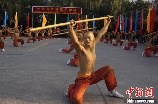 Các võ sinh Thiếu Lâm với thân hình mạ đồng biểu diễn bài quyền đẹp mắt với trường côn. Côn là một trong 18 loại binh khí dùng trong võ thuật cổ truyền Trung Quốc cũng như Việt Nam và được xếp vào hàng "binh khí chi vương" (vua các loại binh khí). Ảnh: chinanews.com.