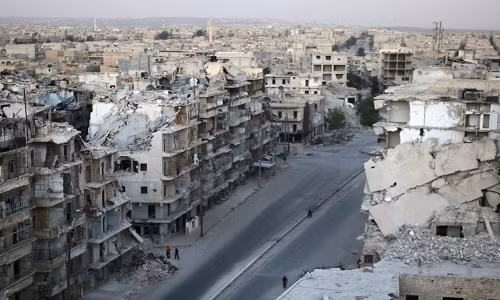 Người dân đi qua những tòa nhà cao tầng bị phá hủy ở khu Tariq al-Bab hôm 5/10.