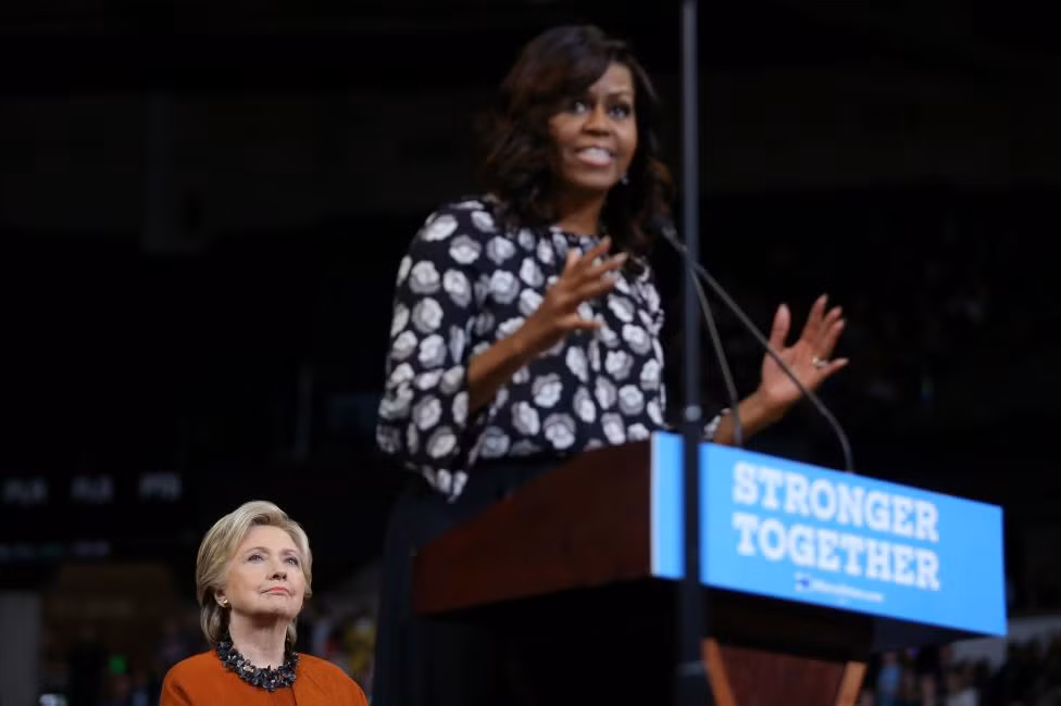 Cựu Ngoại trưởng Mỹ đứng phía sau lắng nghe bà Michelle Obama phát biểu hôm 27/10.
