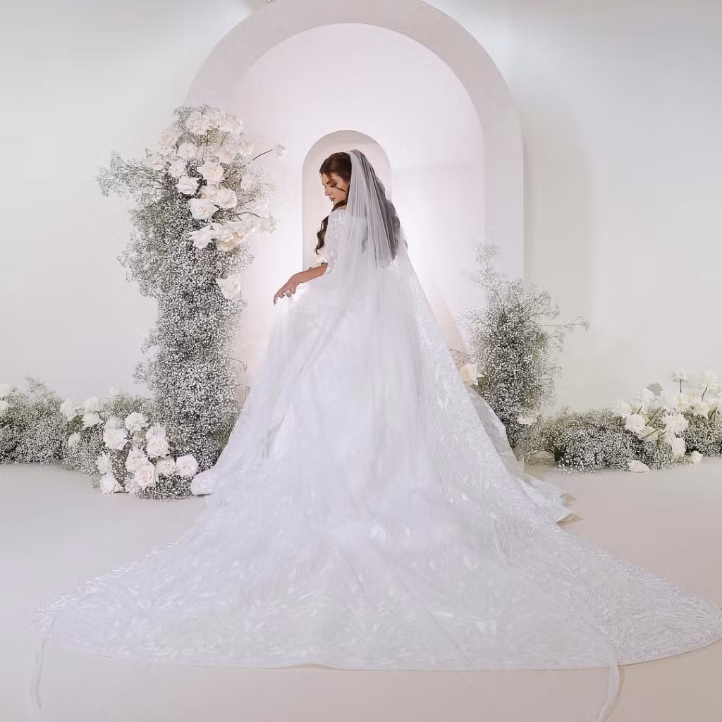 Công chúa Sheikha để tóc dài bồng bềnh, đội khăn voan thêu, trang điểm mắt khói đặc trưng và môi màu nude tự nhiên.