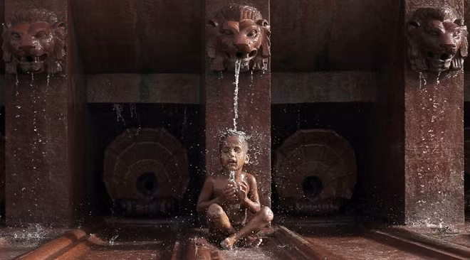 Một bé trai tắm dưới vòi phun nước ở thủ đô New Delhi. Ấn Độ là nước thiệt hại nặng nề nhất do trời nắng hạn. Theo AP, ít nhất 300 người đã tử vong do trời nóng khi nhiệt độ tháng 4 vượt mức 44 độ C. Phần lớn các nạn nhân là người vô gia cư.