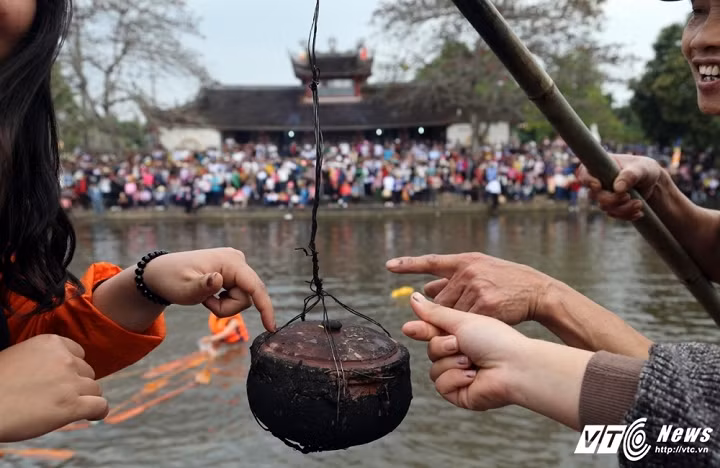 Những niêu cơm chín khi mang lên bờ sẽ có nhiều người dùng tay chạm vào vung. Theo quan niệm, những ai chạm tay đầu tiên vào niêu cơm chiến thắng sẽ gặp may cả năm. (Ảnh: Quang Minh)