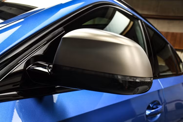 Bên cạnh tông màu chủ đạo là xanh dương, BMW X6 M50i Riverside Blue còn được tô điểm bởi các chi tiết tối màu. Kính chiếu hậu của xe có phần trên màu xám mờ kết hợp cùng màu đen ở phần dưới. Vị trí các cột trên xe và giá nóc sử dụng màu đen bóng tạo nét tương phản.