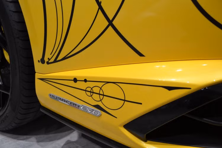 Trong lần này, tay nghề của Dr.Woo đã được thể hiện trên một chiếc Lamborghini Huracan Evo Spyder màu vàng Giallo Inti. Phản ánh các đường nét hình học mạnh mẽ, hình dạng góc cạnh và thậm chí cả họa tiết chữ Y quen thuộc trong thiết kế của Lamborghini, ‘hình xăm’ của Dr.Woo trên thân xe làm nổi bật sự năng động của chiếc xe.