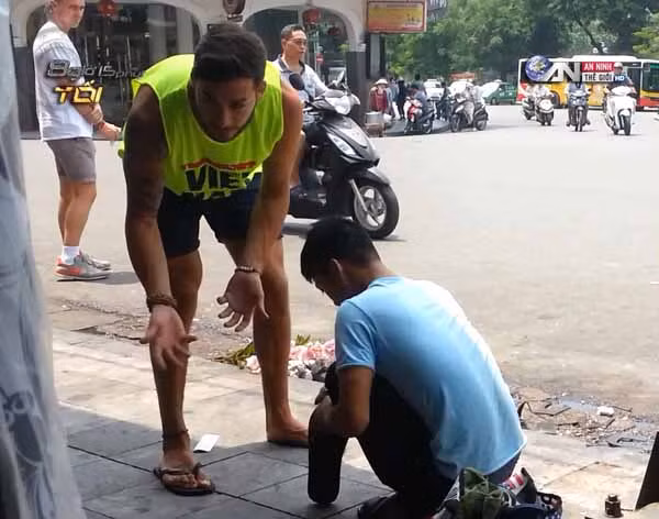 Một du khách bị ép buộc phải sửa đôi dép của mình khi đang đi lại ở phố cổ.