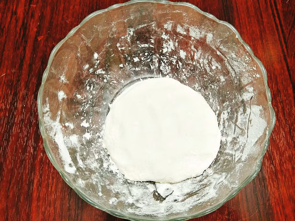 Hướng dẫn cách làm: Bạn cho bột nếp vào âu, thêm muối, dầu ăn rồi trộn đều sau đó cho từ từ từng ít nước nóng vào trộn đều tới khi thấy hỗn hợp bột vừa đủ ẩm thì dừng lại, lấy bột ra mặt phẳng sạch nhồi cho tới khi bột thành một khối dẻo mịn mà không dính tay là được. Bọc kín khối bột và để bột nghỉ 20 phút.