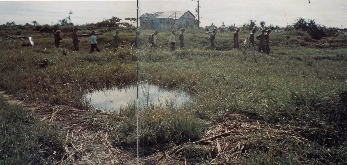 Một tiểu đội bộ đội Giải phóng đi ngang qua một hố bom trên cánh đồng ở ngoại ô Đông Hà.