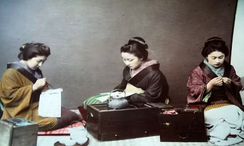 Một số phụ nữ ngồi thêu thùa, may vá.