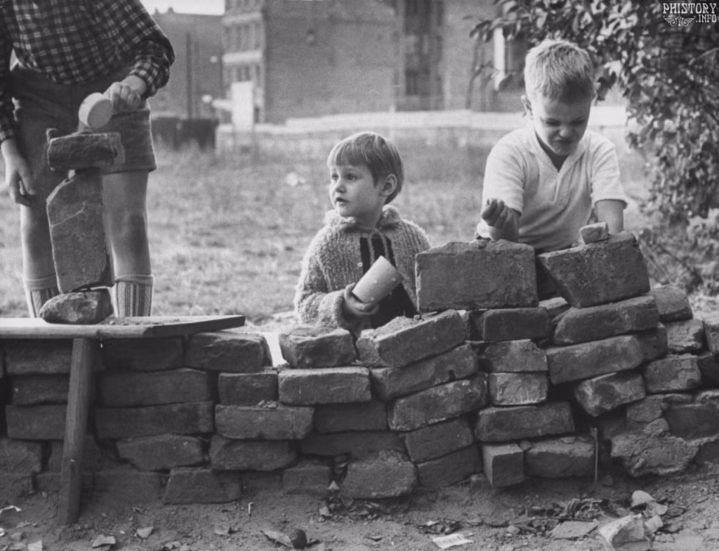 Những bé trai người Đức nghịch ngợm, đóng giả việc xây một bức tường năm 1961.