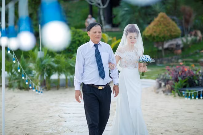 Cô dâu Lan Anh được cha dẫn vào địa điểm làm lễ. Đi trên con đường tình yêu trải đầy hoa, cô gái sinh năm 1989 không giấu được vẻ bồi hồi, xúc động.