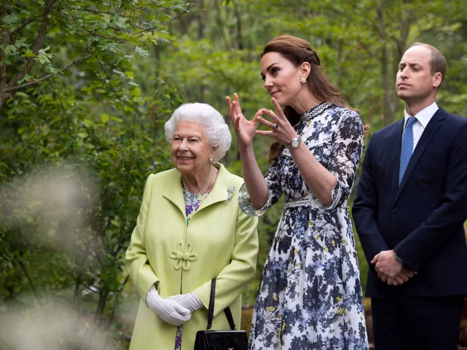 Công nương Kate đang giới thiệu với Nữ hoàng Elizabeth II về khu vườn mà cô thiết kế dành cho Triển lãm hoa Chelsea ở London, trong khi Hoàng tử William đứng cạnh trông giống như một vệ sĩ bảo vệ cho vợ mình.