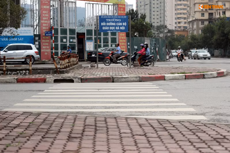 Người đi bộ sau khi đi qua vạch kẻ dưới lòng đường sẽ phải chui dưới tấm biển ghi chữ "Trường bồi dưỡng cán bộ giáo dục Hà Nội" cắm ngang trên vỉa hè.