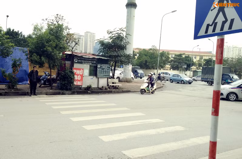 Người đi bộ di chuyển theo vạch kẻ sẽ phải luồn lách qua cây xanh, nhà tạm của một điểm trông giữ xe. Ảnh chụp trên đường Nguyễn Chánh.