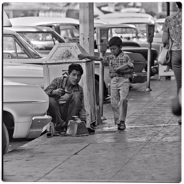 Một thanh niên đánh giày và cậu bé bán kẹo cao su kiếm sống trên đường phố Tijuana năm 1964.