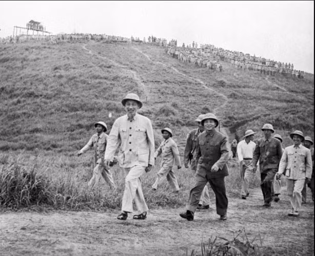 Chủ tịch Hồ Chí Minh (trái) giản dị cùng Đại tướng Võ Nguyên Giáp (thứ 2 từ trái sang) đi thăm một đơn vị quân đội đóng quân ở một địa điểm bí mật năm 1957.