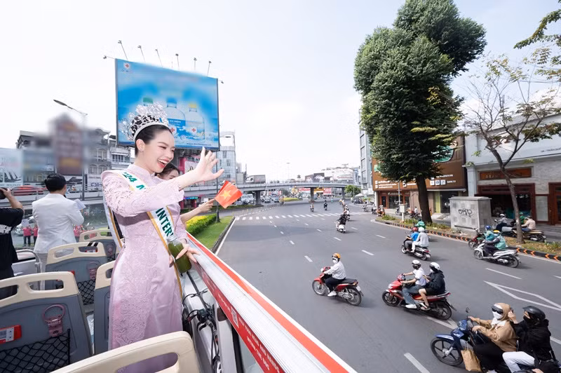 Đứng trên xe buýt 2 tầng, Hoa hậu Thanh Thủy luôn tươi cười và thân thiện vẫy tay chào người hâm mộ theo dõi hành trình.
