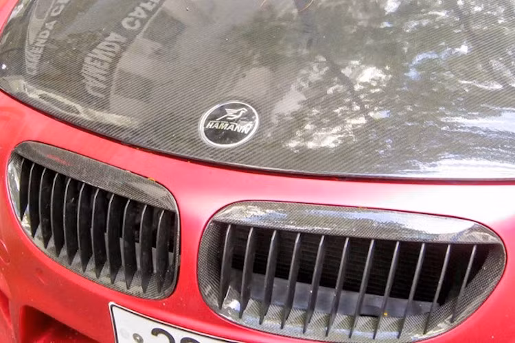 Một số món "đồ chơi" bằng sợi carbon từ Hamann như lưới tản nhiệt và nắp ca-pô cũng khiến chiếc xe trở nên nổi bật hơn và tạo điểm nhấn trên thân xe đỏ mờ.