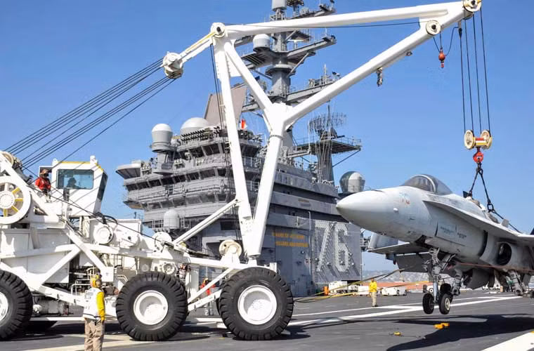 Thủy thủ đang sử dụng xe cẩu để cẩu chiếc tiêm kích F/A-18 Hornet trên tàu sân bay USS Ronald Reagan (CVN-76).