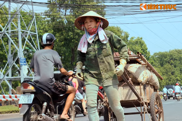 Người phụ nữ gồng vai, kéo chiếc xe cải tiến chở đầy rác thải dưới cái nắng trên 40 độ C.