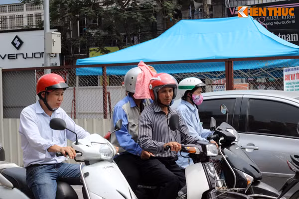 Hình ảnh ghi lại một người dân dùng khăn phủ lên phía trước chiếc mũ bảo hiểm đang đội trên đầu để giảm bớt đi không khí nóng nực. Ảnh chụp trên đường Cầu Giấy.