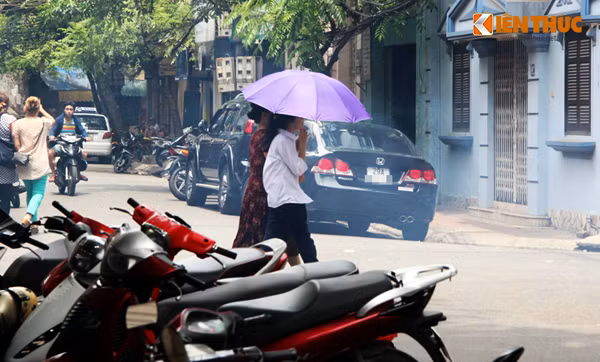 Nhiều người đi bộ sử dụng ô vừa để che nắng, vừa để chắn khói bay vào mặt. Ảnh chụp trên phố Hồng Phúc.