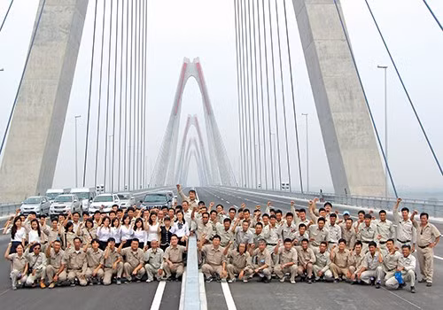 Niềm vui sướng lớn nhất có lẽ thuộc về những người thợ đã góp sức xây nên cây cầu (Trong ảnh: Các chuyên gia, kỹ sư và công nhân nhà thầu Sumitomo Mitsui, thi công gói thầu số 1, trong ngày cây cầu gần hoàn thiện).