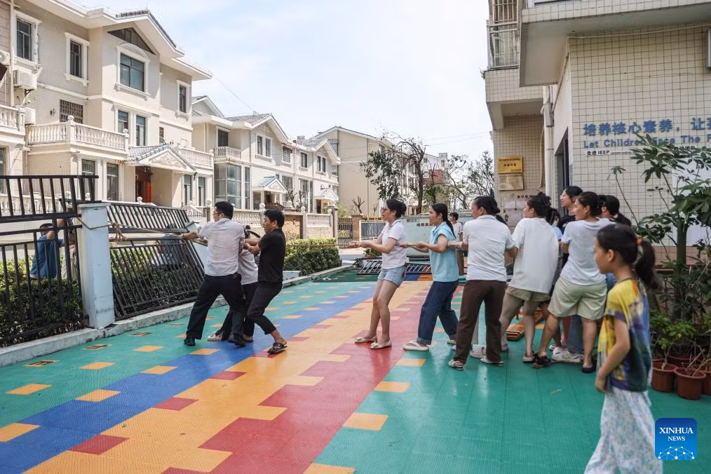 Các giáo viên kéo hàng rào bị nghiêng tại một trường mẫu giáo ở Hải Khẩu, tỉnh Hải Nam, ngày 8/9.