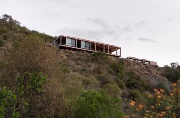 Ngôi nhà này do Alarciaferrer Arquitectos thiết kế, nhìn ra thung lũng Camlamuchita ở Argentina và có hai tầng: Tầng trên nhô ra trên núi, chủ yếu dành cho không gian chung, và tầng dưới có phòng ngủ, hồ bơi.