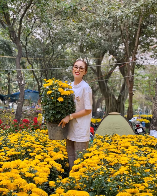 Người đẹp diện bộ đồ giản dị, tươi tắn chụp hình bên những chậu cúc vàng.