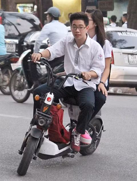 Không chỉ "hiên ngang" không đội mũ bảo hiểm khi điều khiển xe máy điện, các bạn sinh học còn túm năm, tụm ba, dàn hàng ngang trên các con phố, khiến việc di chuyển của những người xung quanh rất khó khăn.
