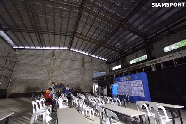 Có thể thấy, phòng họp báo trông giống như được tổ chức ở trong một nhà kho, với những chiếc ghế nhựa và những chiếc bàn cũ kỹ. Chỉ có duy nhất một chiếc phông của BTC SEA Games 30 là nổi bật giữa đám "tiện nghi tối cổ". Ảnh: Siamsport
