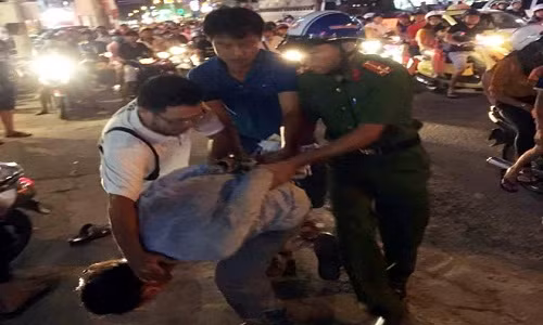 Thanh niên chặn ôtô bẻ gương chiếu hậu bị người dân, công an khống chế. Ảnh: B.H.Y.