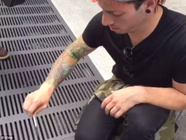 Một thành viên của ban nhạc Twenty One Pilots 'chơi trội' khi nhét điện thoại qua khe nắp cống. (Nguồn: Dailymail).