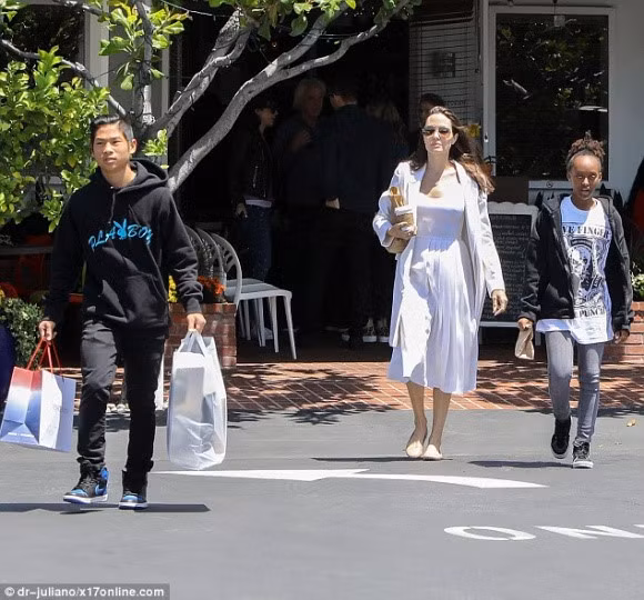 Diễn viên Angelina Jolie cũng bị bắt gặp ra ngoài mua sắm một số đồ cần thiết cùng với hai con là Pax Thiên và Zahara. Anh trai Pax Thiên ra dáng một cậu thanh niên chững chạc khi giúp mẹ và em gái xách đồ.