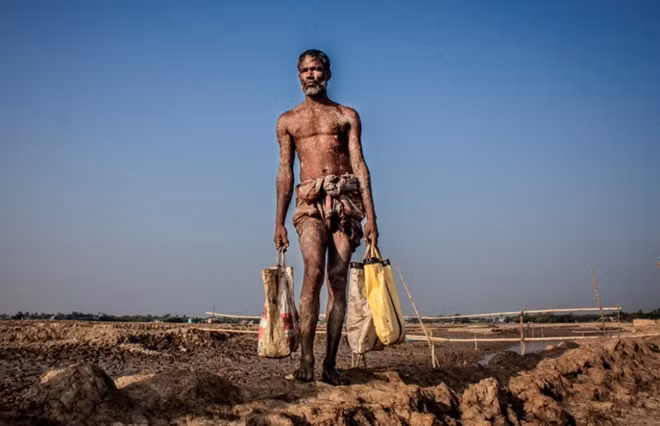 Hình ảnh người nông dân bắt cua trên mảnh đất cằn ở huyện Satkhira, Bangladesh. Độ mặn trong đất ở nơi đây đang khiến đất nông nghiệp ở vùng này dần không còn thích hợp cho các loại cây trồng. Cuộc thi nhiếp ảnh về môi trường thế giới được tổ chức hằng năm (bắt đầu từ năm 2007) nhằm khuyến khích sự tham gia của các nhiếp ảnh gia chuyên và không chuyên trên khắp thế giới có những tác phẩm mang tính sáng tạo, thời sự... và truyền tải được thông điệp về bảo vệ môi trường. Ảnh: Kazi Riasat Alve.