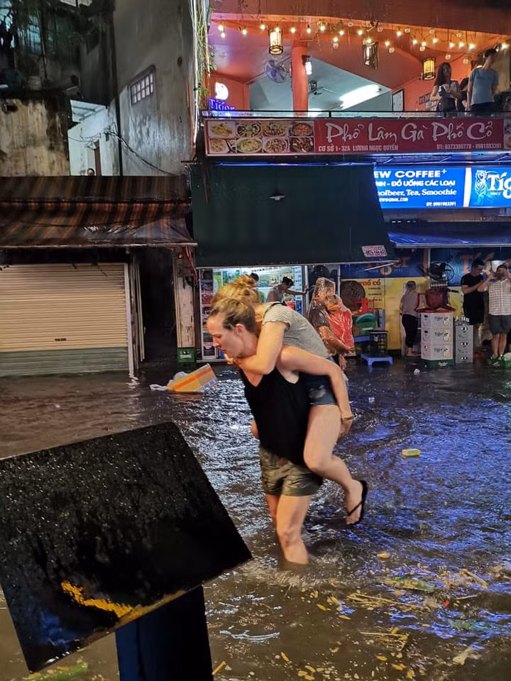 Do không chờ được mưa tạnh và nước rút, đôi bạn phải cõng nhau về.