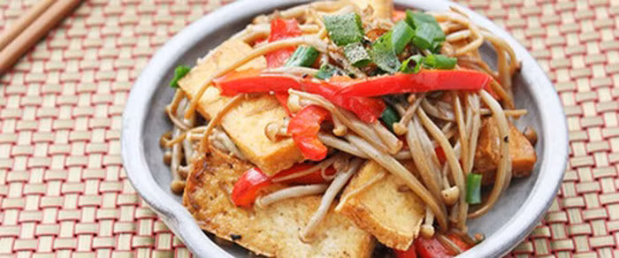 Phi thơm hành, tỏi băm và cho đậu phụ vào đảo qua, cho cà rốt, nấm, vào đảo nhanh tay trên lửa lớn, nêm thêm gia vị vừa miệng. Khi các nguyên liệu vừa chín tới thì cho giá vào xào qua. Cuối cùng cho hành mùi và rắc hạt tiêu lên trên. Ảnh: Cachnauanngon.