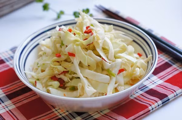Ớt sừng cắt nhỏ, bỏ hạt, cho vào chén cùng 2 muỗng canh giấm, 2 muỗng canh nước mắm, 1 muỗng canh đường trắng, khuấy đều. Cho bắp cải vào, trộn đều. Cho bắp cải muối vào ngăn mát tủ lạnh, để qua đêm là có thể dùng. Ảnh: NiemDamMe.com.vn.