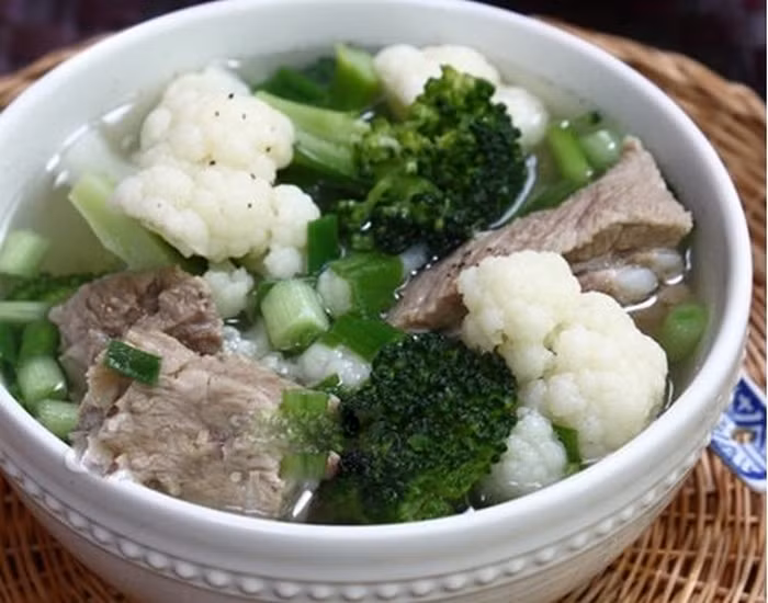 Sườn mềm, cho hai loại súp lơ vào nồi, nêm 1 thìa nhỏ nước mắm, 1/2 thìa nhỏ muối. Vì súp lơ và sườn đều rất ngọt nên bạn không cần nêm nếm nhiều gia vị tạo ngọt như hạt nêm hay mì chính nữa. Đậy vung đun khoảng 2-3 phút rồi nêm nếm lại tùy theo khẩu vị của bạn, rắc hành lá, rau mùi đã thái nhỏ vào nồi. Ảnh: Giadinh.