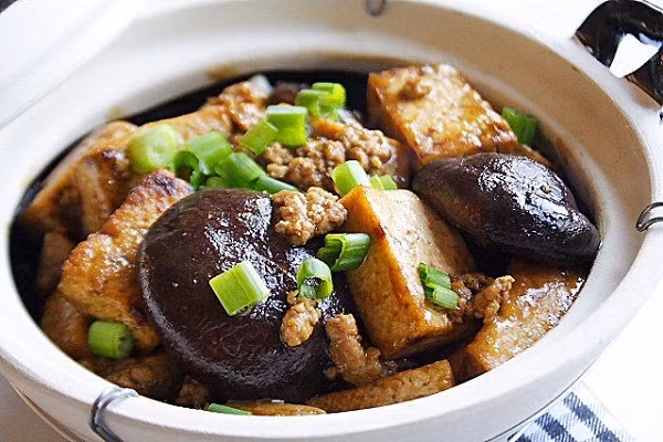 Tiếp theo cho bột ngô hòa tan vào chảo để tạo độ sánh cho món ăn, cho đậu phụ chiên vào đảo nhẹ tay. Cho đậu phụ cùng các loại rau củ sang nồi đất rồi cho nước dùng vào đậy kín nắp và đun sôi là được. Ảnh: monngonmienbac.net.