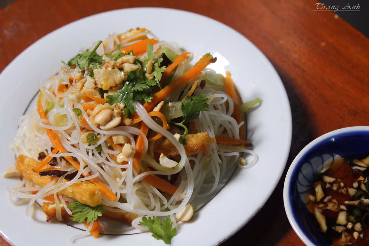 Phi thơm hành, thêm phần nấm tàu hũ ky, cà rốt, cần tây, vào đảo cho đều tay. Xào như vậy khoảng 3 phút thì thêm phần đậu hũ chiên và hỗn hợp nước tương đã pha vào. Tiếp đến là nêm sa tế rồi cho tiếp bún vào xào chung, đảo đều là món ăn đã hoàn thành. Ảnh: yeunoitro.net.