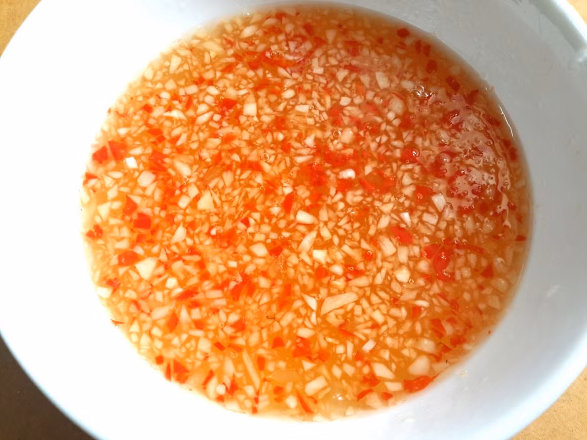 Thịt ba chỉ luộc chín với nước dừa, muối, củ hành. Thịt chín vớt để nguội rồi cắt mỏng. Vẫn nồi nước luộc thịt cho tôm vào luộc vừa chín tới vớt ra để nguội, lột vỏ, bỏ chỉ đen. Nước trộn gỏi: đường, chanh, nước mắm, tỏi, ớt. Trộn thịt và tôm vào 1 cái tô cho 1 nửa nước trộn gỏi vào trộn đều cho thấm khoảng 10 - 15 phút. Ảnh: bepgiadinh.com.