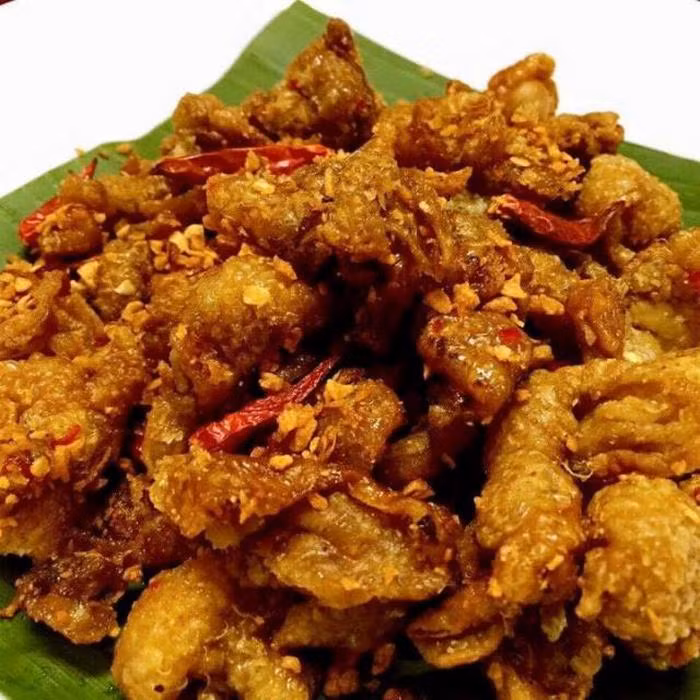 Bắc chảo lên bếp, cho dầu ăn chiên da gà ngập dầu trên lửa lớn. Sau đó, vớt da gà ra để ráo mỡ. Sau đó phi thơm tỏi và cho nước sốt đã pha vào đảo đều rồi cho da gà vào nấu cho đến khi keo lại sền sệt là được. Ảnh: Cahlammonngon.