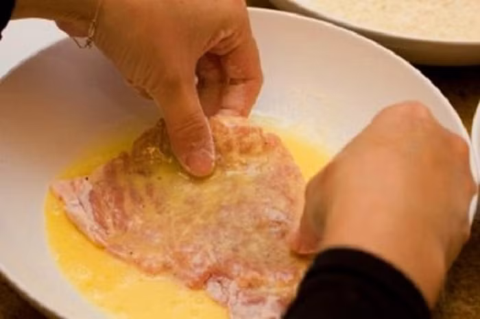 Thịt chiên xù kiểu Nhật. Nguyên liệu gồm thịt nạc vai, trứng gà, vài lá tía tô, phô mai thái lát, bột mì, bột chiên xù. Thái thịt miếng dày khoảng 0,5 cm rồi đập dập cho thịt mềm. Rắc chút muối và tiêu lên rồi để tủ lạnh khoảng 10 phút. Ảnh: Homnayangi.