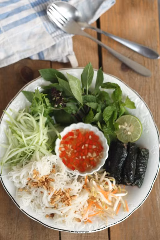 3. Thịt bò nướng lá lốt. Nguyên liệu: Thịt bò, lá lốt, gia vị, dầu ăn, tỏi + ớt + đường để pha mắm. Lấy một ít lá lốt thái chỉ trộn vào thịt, nêm gia vị, cuộn thịt. Thoa lên lá lốt chút dầu ăn để lá khỏi bị cháy khô khi nướng. Ăn kèm bánh tráng cuốn và rau sống. Ảnh: cooky.vn.