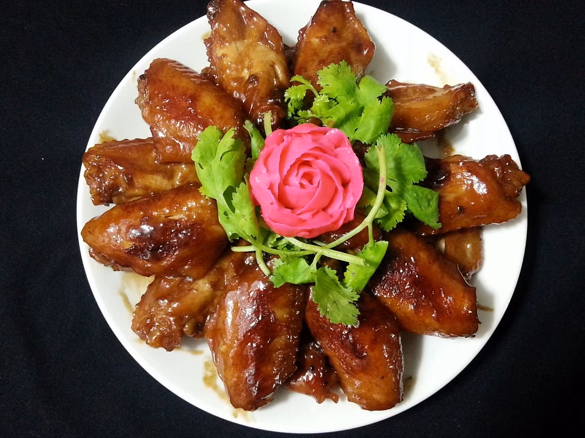 Tiếp tục kho, không cần đậy nắp. Khi Coca Cola cạn gần hết, cho tương ớt vào, trộn đều. Cho cánh gà vào khay nướng có lót giấy bạc. Nướng ở nhiệt độ 200ºC trong khoảng 5-7 phút, da gà vàng đẹp mắt thì lấy ra. Cho gà rim Coca Cola ra đĩa. Dùng làm món nhắm hay ăn nóng với cơm đều ngon. Ảnh: kenhphunu.com.