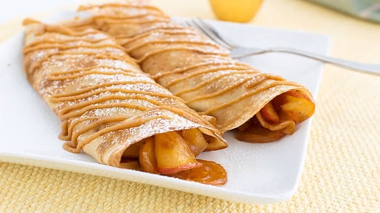 Đun vài phút thì tắt bếp. Cuối cùng trải một miếng vỏ bánh vào một chiếc đĩa, sau đó xúc nhân bánh rải đều theo chiều dọc của bánh. Thêm một ít sữa chua lên trên phần nhân nữa rồi khéo léo cuộn chiếc bánh lại là hoàn thiện. Ảnh: Monngon.tv.