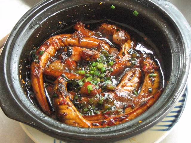 10. Cá bống dừa kho thịt ba rọi. Nguyên liệu: cá bống dừa, thịt ba rọi, hành, tỏi băm, rau răm, đường, nước mắm, nước màu dừa, tiêu hạt đập dập. Làm sạch cá, dội qua nước sôi vào thịt, thái miếng bằng ngón tay. Cho cá, thịt xếp lớp vào nồi đất. Ướp nước màu dừa, mắm, đường, tiêu, trong 20 phút. Cho lên bếp lửa riu riu, đến khi nước trong cá sền sệt thì phi hành tỏi thơm, hành lá cho vào nồi cá đun thêm 1 phút. Ảnh: chanthanh-truly.com.