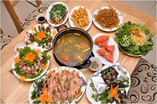 Ninh xương lấy nước dùng. Cá lọc thịt, thái miếng vừa ướp gia vị. Thịt bò thái mỏng ướp vài lát gừng thái chỉ. Lòng non, dạ dày làm sạch thái miếng vừa ăn. Ngao rửa sạch bày lên đĩa. Rau các loại rửa sạch để ráo, đậu phụ thái miếng, cà chua bổ múi cau. Ảnh: phunutoday.vn.